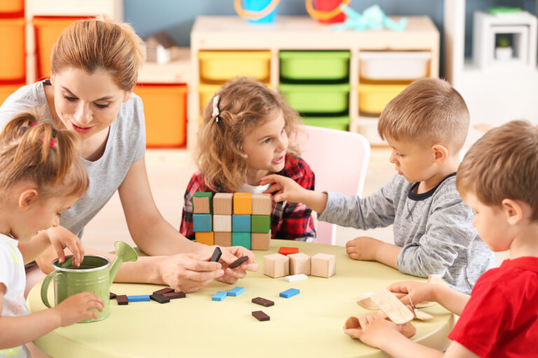 Nursery teacher with cute little children in kindergarten